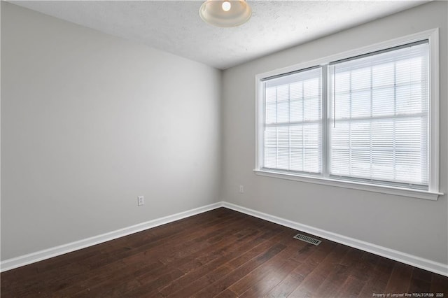 unfurnished room featuring dark wood-type flooring and a textured ceiling