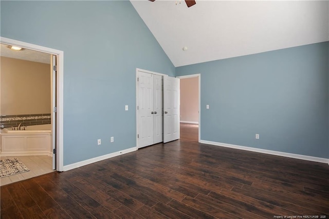 unfurnished bedroom featuring connected bathroom, high vaulted ceiling, dark hardwood / wood-style floors, a closet, and ceiling fan