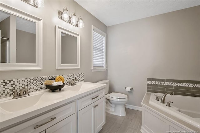 bathroom featuring tasteful backsplash, vanity, toilet, a bath, and a textured ceiling