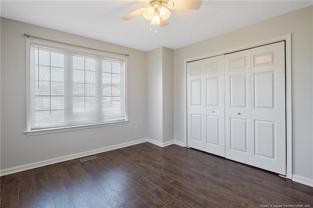 unfurnished bedroom with a closet, dark hardwood / wood-style floors, and ceiling fan