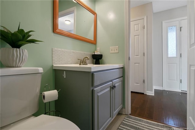 bathroom with vanity, toilet, hardwood / wood-style floors, and decorative backsplash