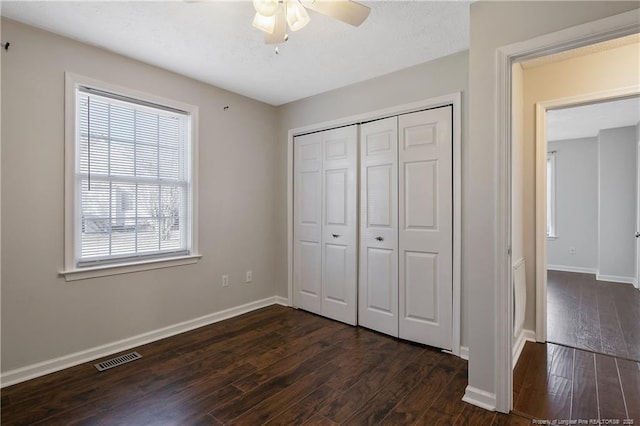 unfurnished bedroom with ceiling fan, dark hardwood / wood-style flooring, and a closet