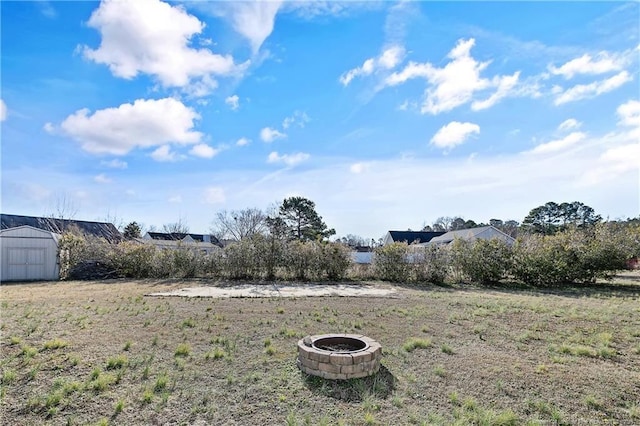 view of yard with a storage shed and an outdoor fire pit