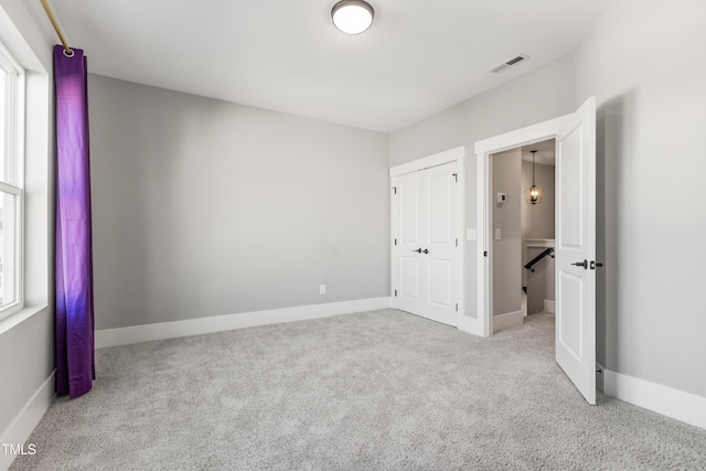 unfurnished bedroom featuring a closet and light carpet