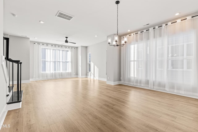 unfurnished living room featuring ceiling fan with notable chandelier and light wood-type flooring