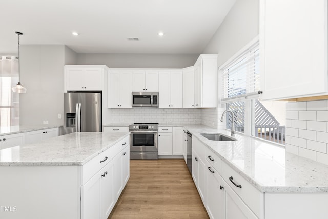 kitchen featuring white cabinetry, stainless steel appliances, decorative light fixtures, and sink