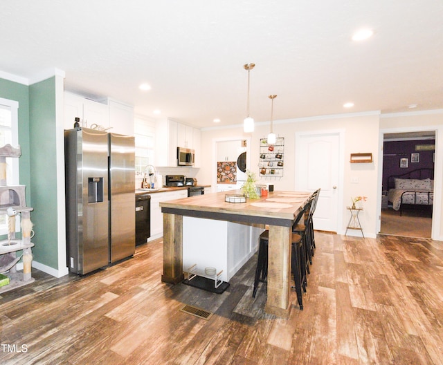 kitchen with black appliances, crown molding, white cabinets, and wood finished floors