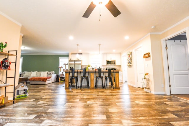 interior space with baseboards, a ceiling fan, wood finished floors, crown molding, and recessed lighting