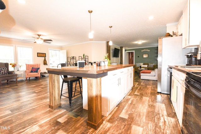 kitchen featuring crown molding, white cabinetry, open floor plan, and wooden counters