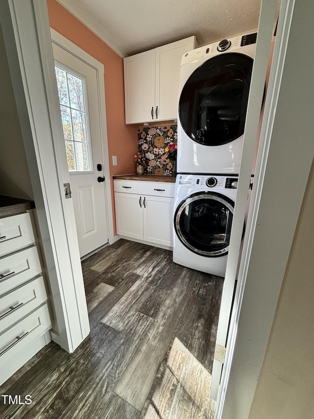 laundry room featuring stacked washer and dryer, dark wood-style flooring, and cabinet space