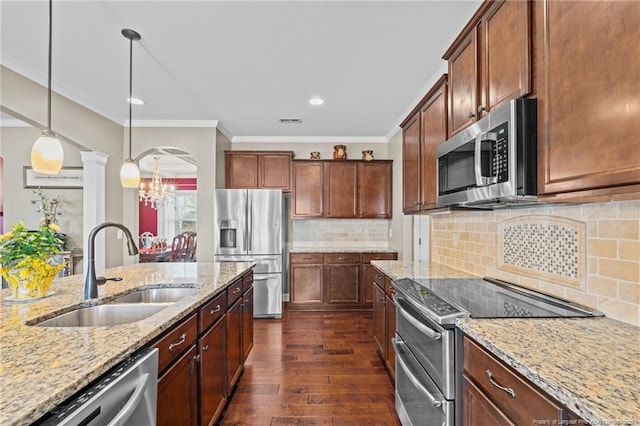 kitchen featuring appliances with stainless steel finishes, pendant lighting, sink, dark hardwood / wood-style flooring, and light stone countertops