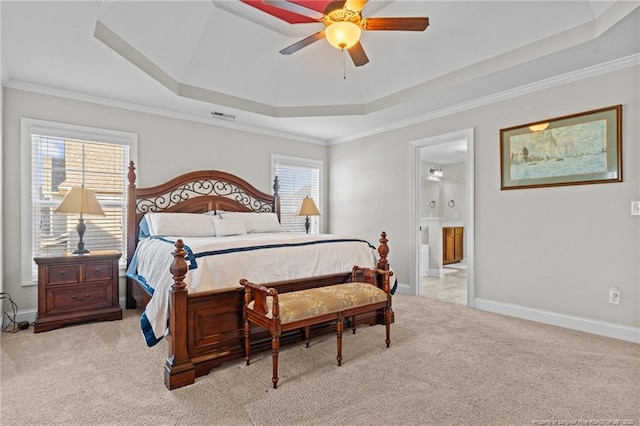 carpeted bedroom with a raised ceiling, ornamental molding, connected bathroom, and ceiling fan