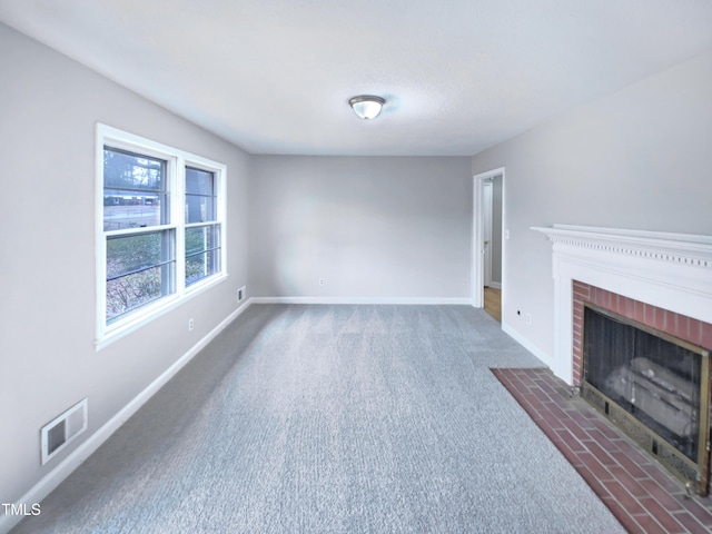 unfurnished living room featuring a brick fireplace and dark carpet