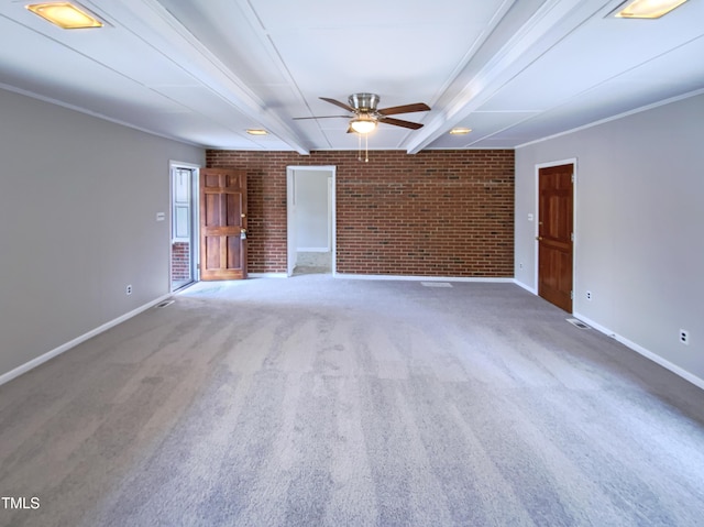 carpeted empty room featuring beam ceiling, ornamental molding, ceiling fan, and brick wall