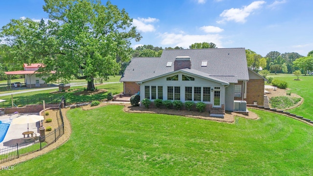 rear view of house featuring central air condition unit and a lawn