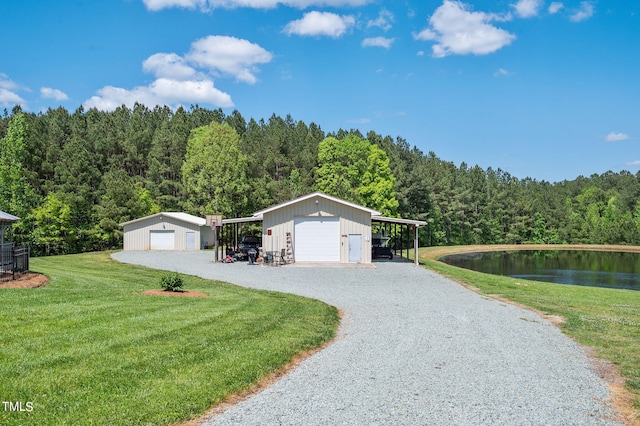 view of front facade featuring a carport, a garage, a water view, an outbuilding, and a front lawn