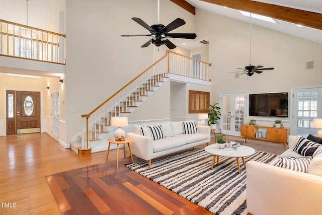 living room featuring hardwood / wood-style flooring, ceiling fan, a towering ceiling, french doors, and beamed ceiling