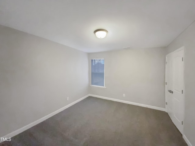 unfurnished room featuring dark carpet