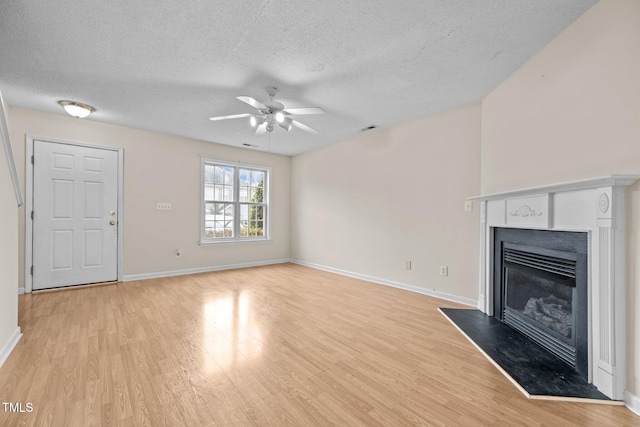 unfurnished living room with ceiling fan, light hardwood / wood-style floors, and a textured ceiling