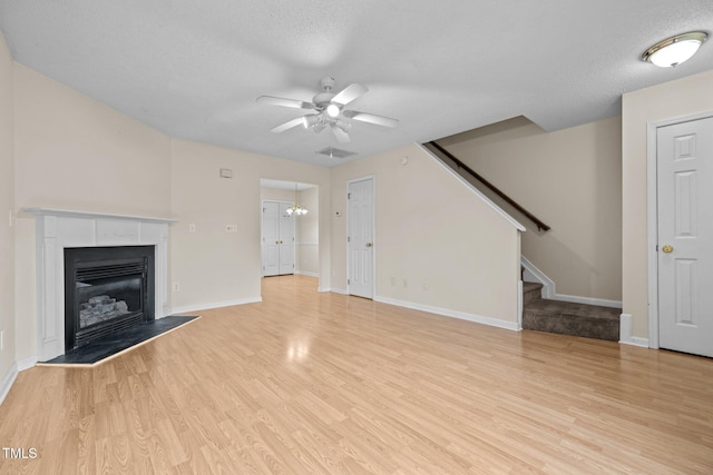 unfurnished living room featuring ceiling fan, light hardwood / wood-style floors, and a textured ceiling