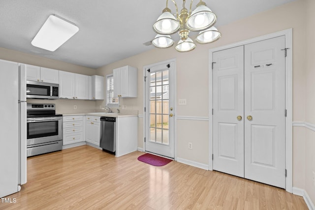 kitchen with white cabinetry, appliances with stainless steel finishes, sink, and light hardwood / wood-style floors