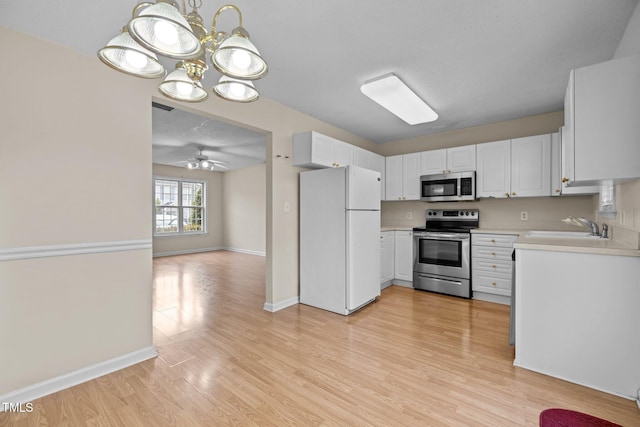 kitchen featuring sink, light hardwood / wood-style flooring, appliances with stainless steel finishes, ceiling fan with notable chandelier, and white cabinets