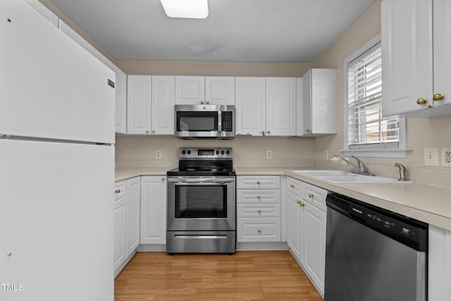 kitchen with white cabinetry, appliances with stainless steel finishes, light hardwood / wood-style floors, and sink