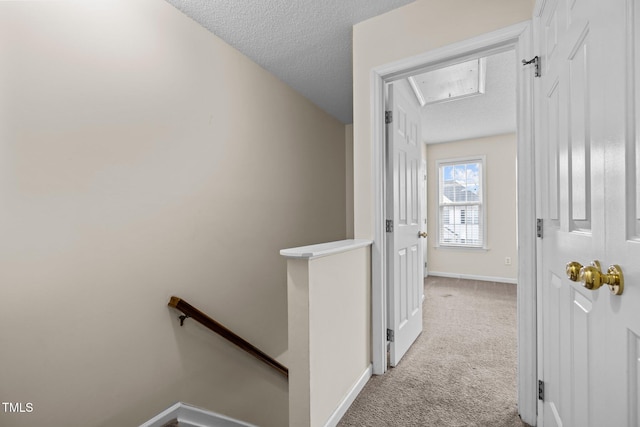 hall featuring light carpet and a textured ceiling