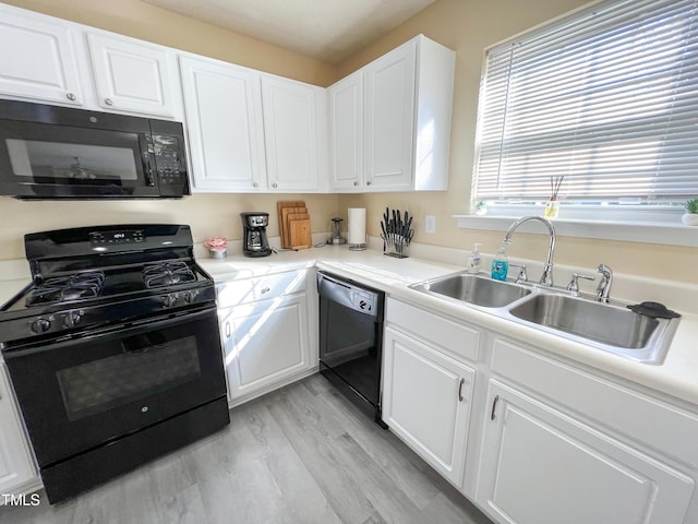 kitchen featuring sink, black appliances, white cabinets, and light wood-type flooring