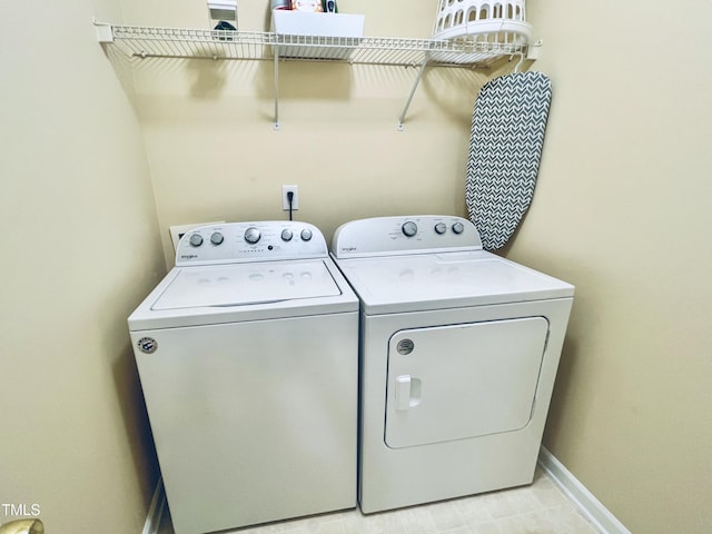 clothes washing area featuring washing machine and dryer, laundry area, and baseboards