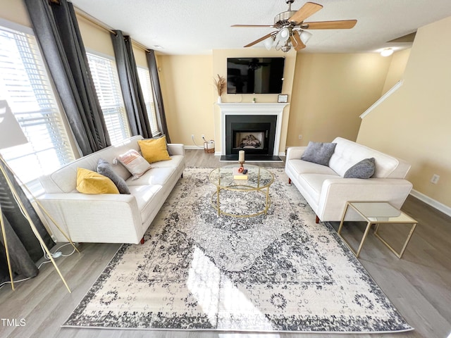 living room with hardwood / wood-style flooring, ceiling fan, and a textured ceiling