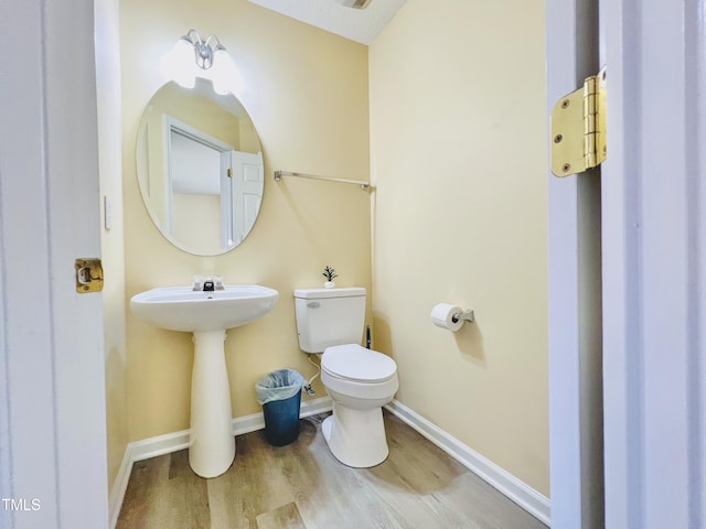 bathroom featuring a sink, wood finished floors, toilet, and baseboards