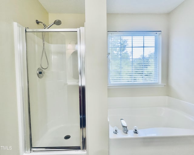 bathroom with a stall shower and a garden tub