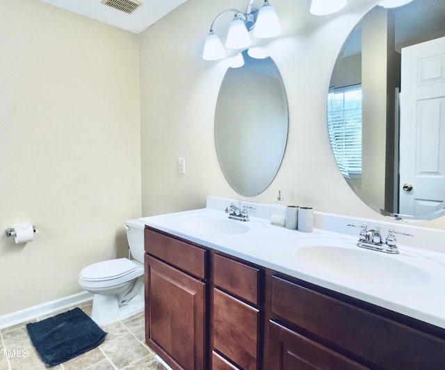 bathroom featuring visible vents, double vanity, a sink, and toilet