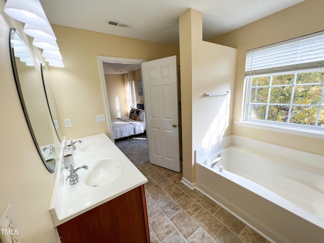 bathroom featuring vanity, a bathtub, and a textured ceiling