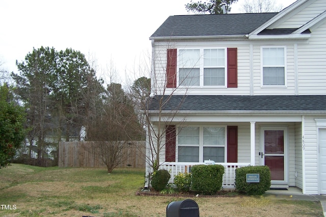 exterior space with covered porch, roof with shingles, fence, and a front lawn