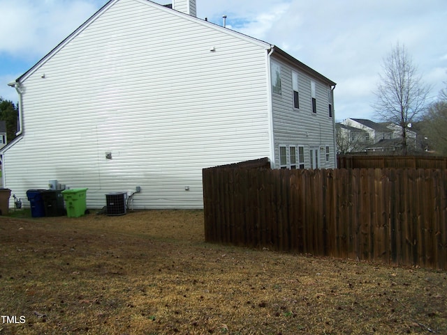 view of side of property featuring central AC and fence