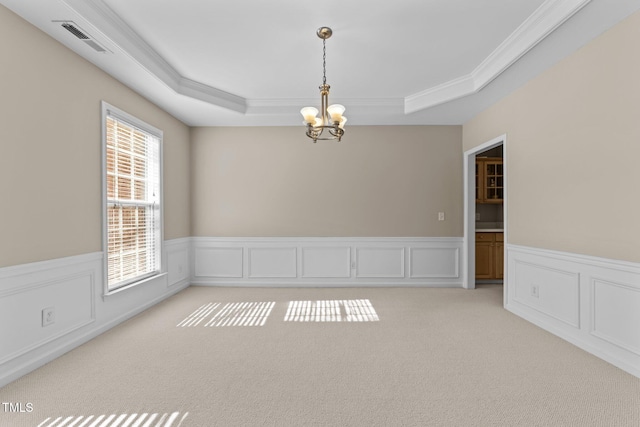 spare room featuring crown molding, light colored carpet, a tray ceiling, and a notable chandelier