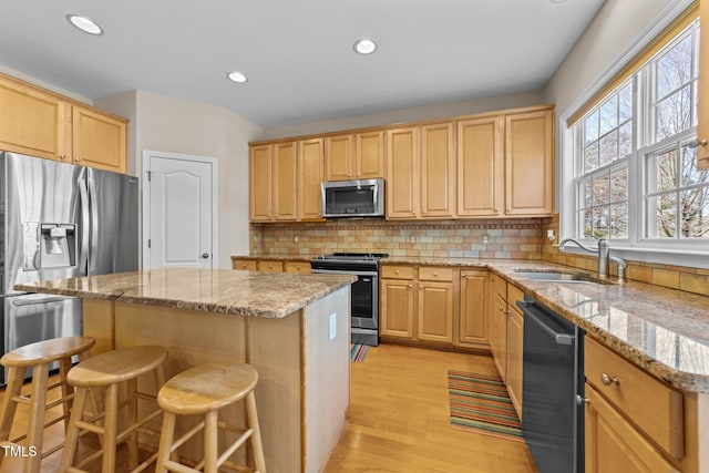 kitchen featuring light brown cabinetry, sink, a center island, a kitchen breakfast bar, and stainless steel appliances