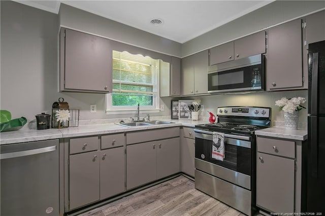 kitchen featuring light hardwood / wood-style floors, stainless steel appliances, gray cabinets, and sink