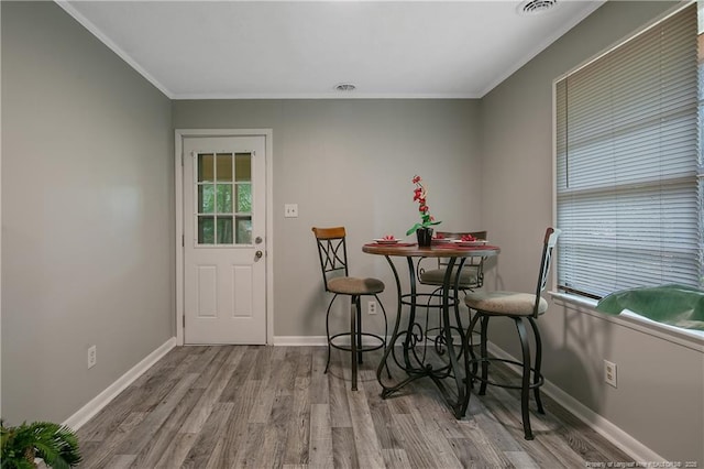 dining space featuring crown molding and light hardwood / wood-style flooring