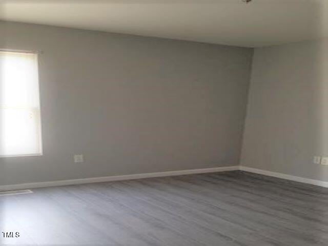 spare room with baseboards and wood finished floors