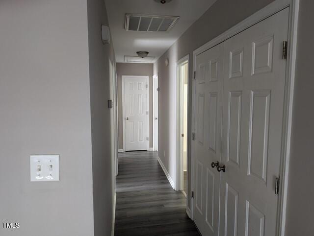 hallway with visible vents, baseboards, and dark wood-style flooring