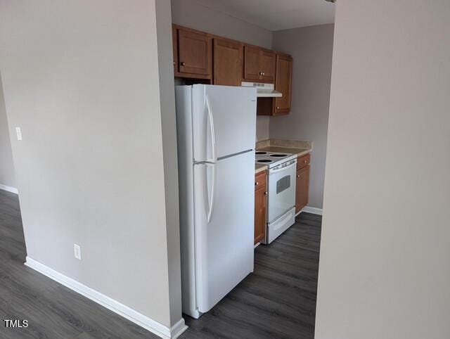 kitchen with under cabinet range hood, baseboards, white appliances, and dark wood-style flooring