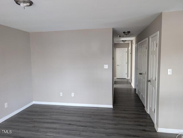 spare room with dark wood-type flooring and baseboards