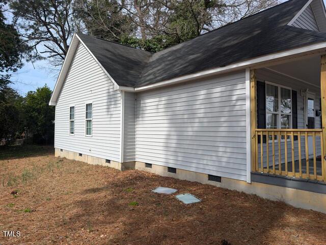 view of side of home with a shingled roof and crawl space