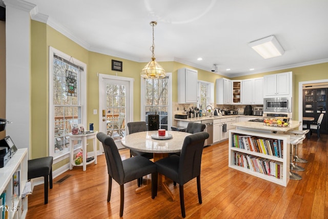 dining space with ornamental molding, a healthy amount of sunlight, light hardwood / wood-style floors, and sink