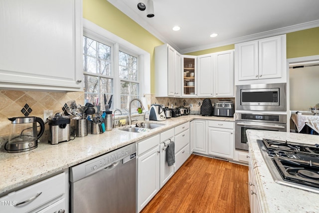 kitchen with stainless steel appliances, white cabinetry, sink, and crown molding