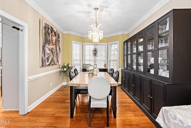 dining space with ornamental molding, a notable chandelier, and light hardwood / wood-style floors