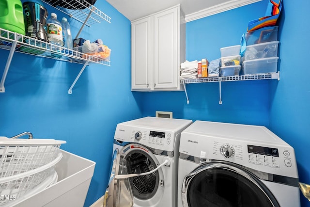 clothes washing area with washer and clothes dryer and cabinets